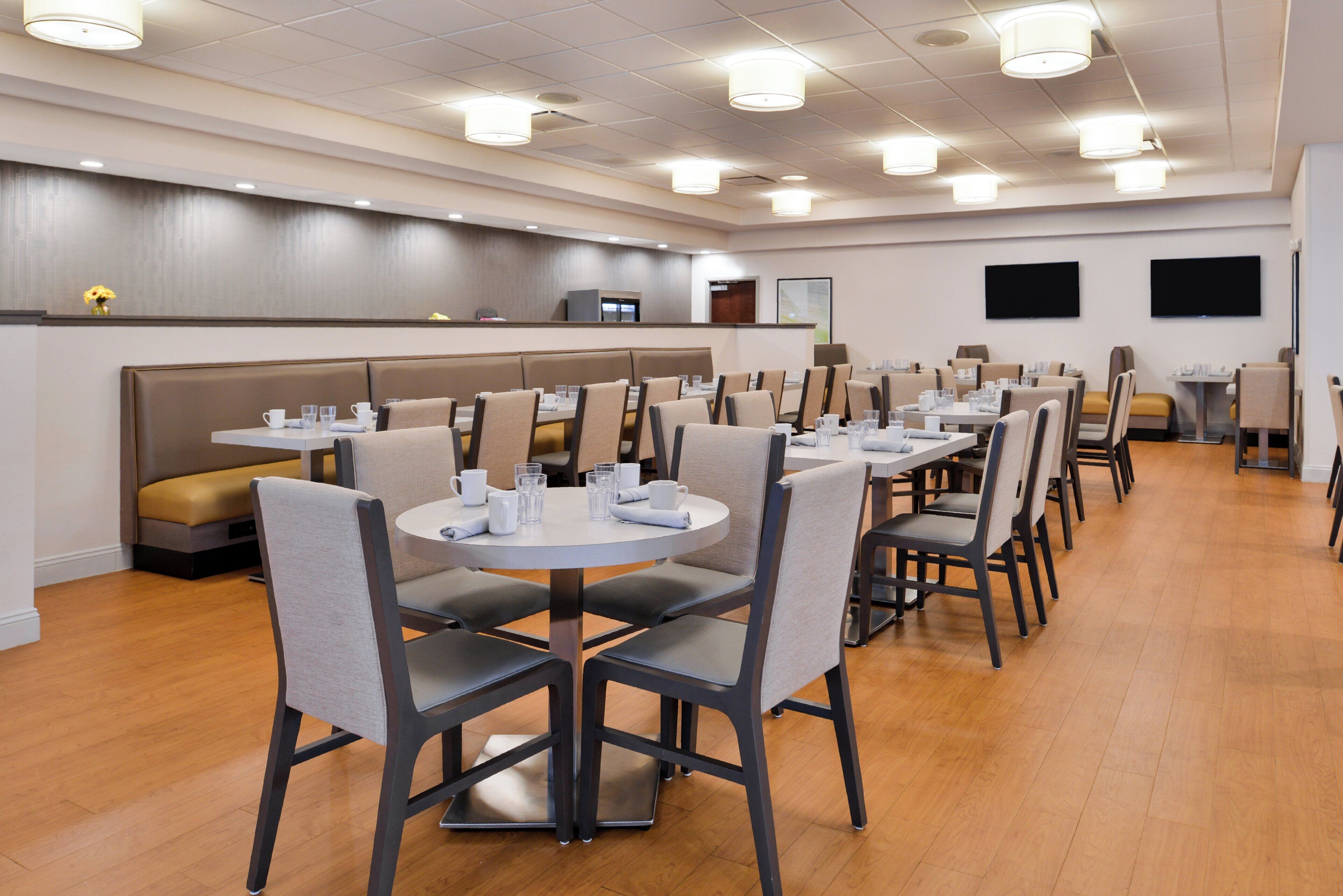A hotel dining area with booths and tables, equipped with chairs and tables set for dining.