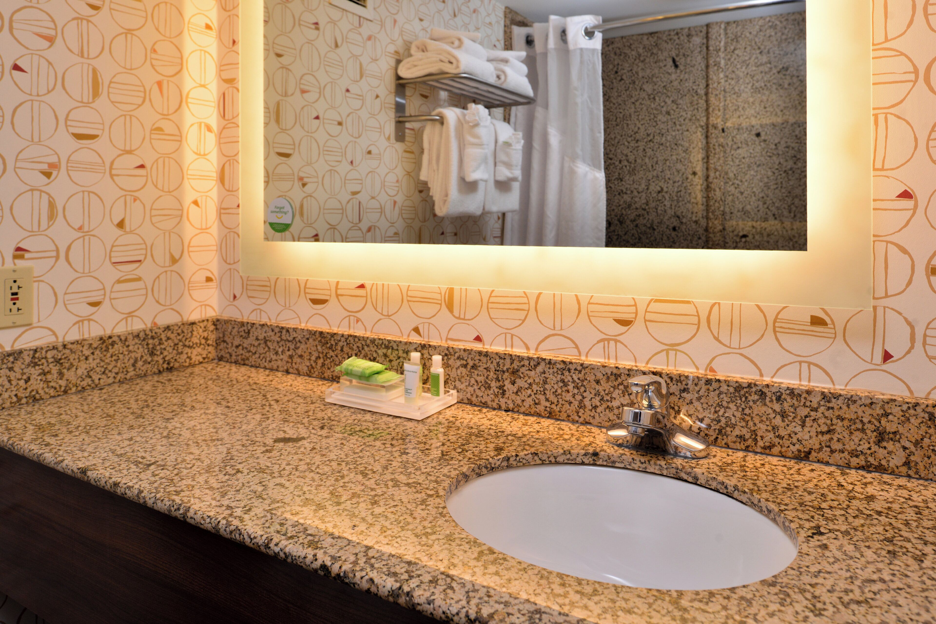 A bathroom with a granite countertop, a sink, a mirror, and a towel rack.