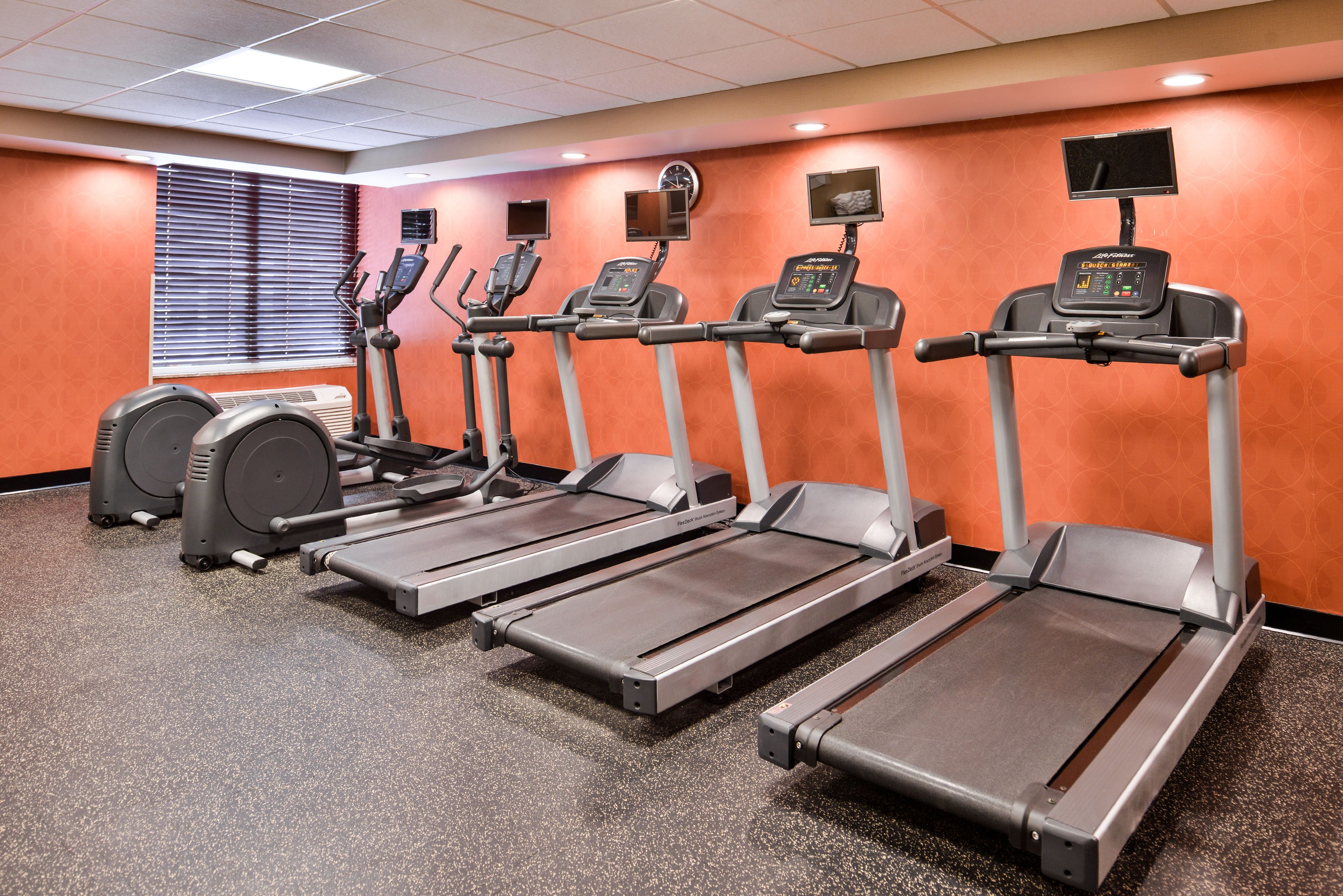 A gym with treadmills, ellipticals, and a stationary bike.
