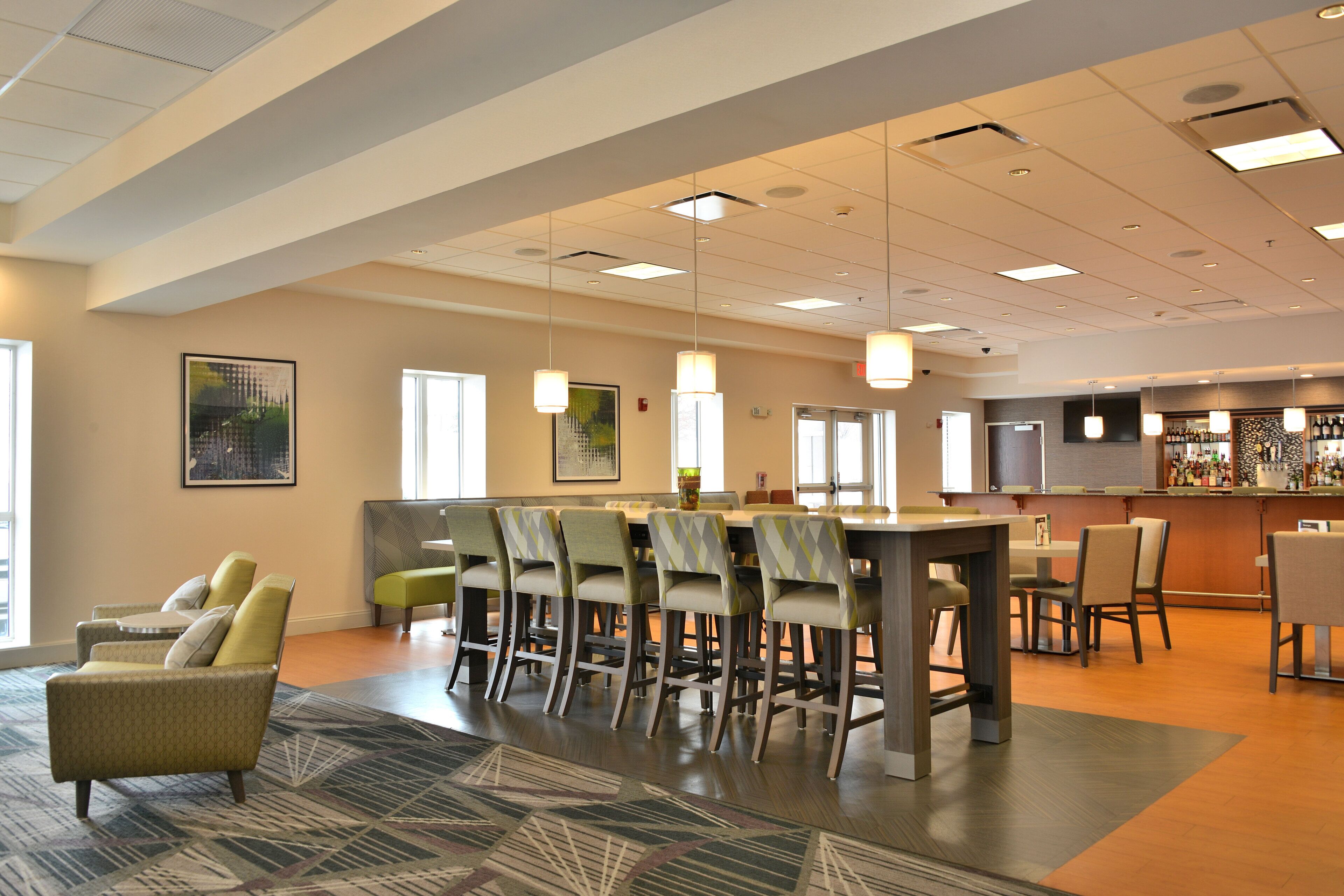 A modern hotel lobby with a bar area, seating arrangements, and artwork on the walls.
