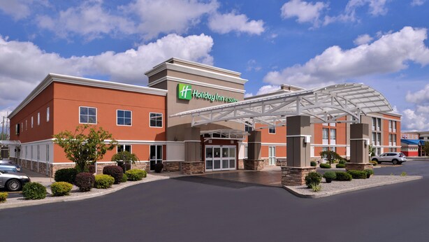 A Holiday Inn Express hotel with a covered entrance, a parking lot, and a clear sky.