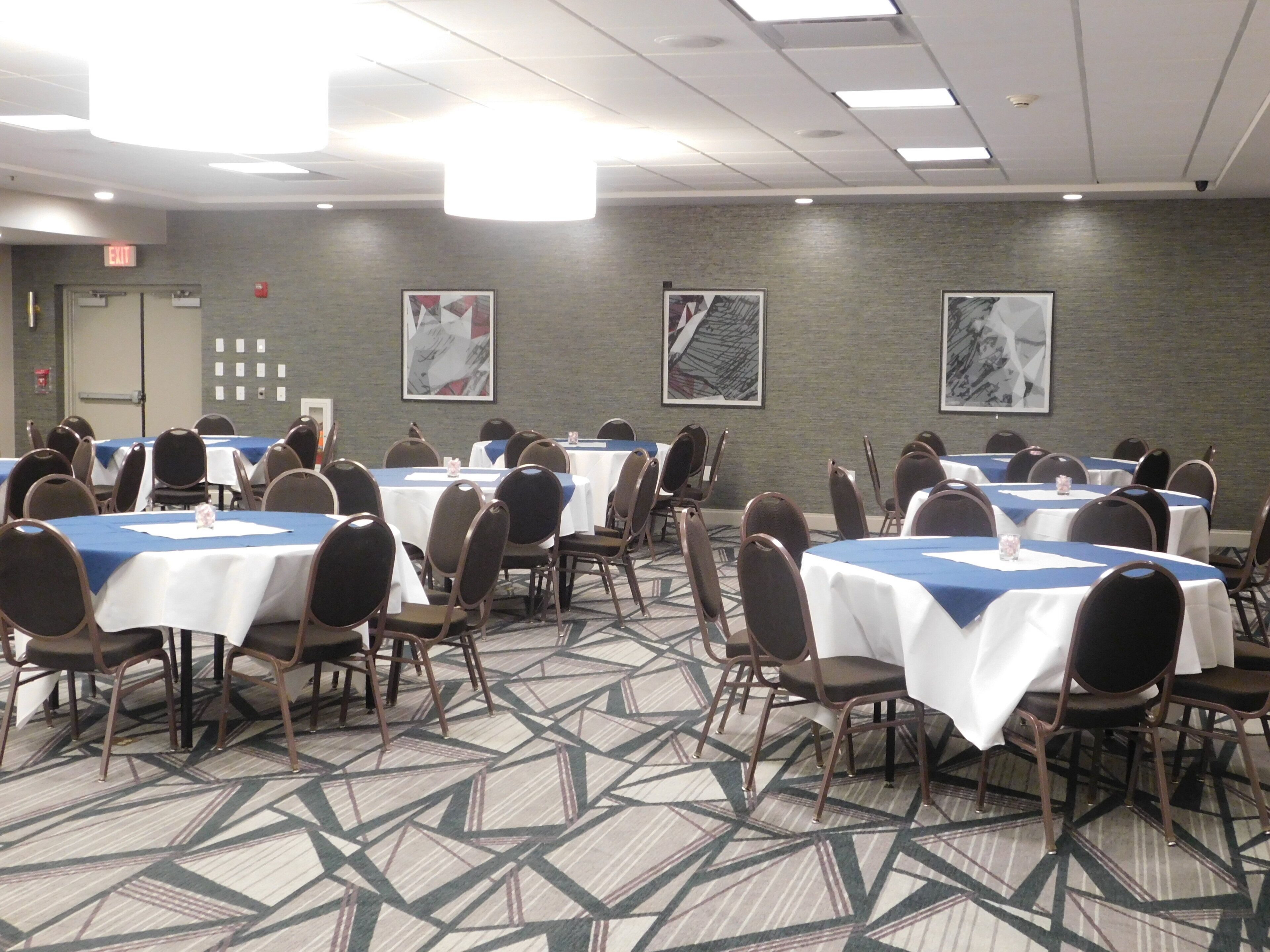 A conference room with multiple tables and chairs, equipped with nameplates and water glasses.