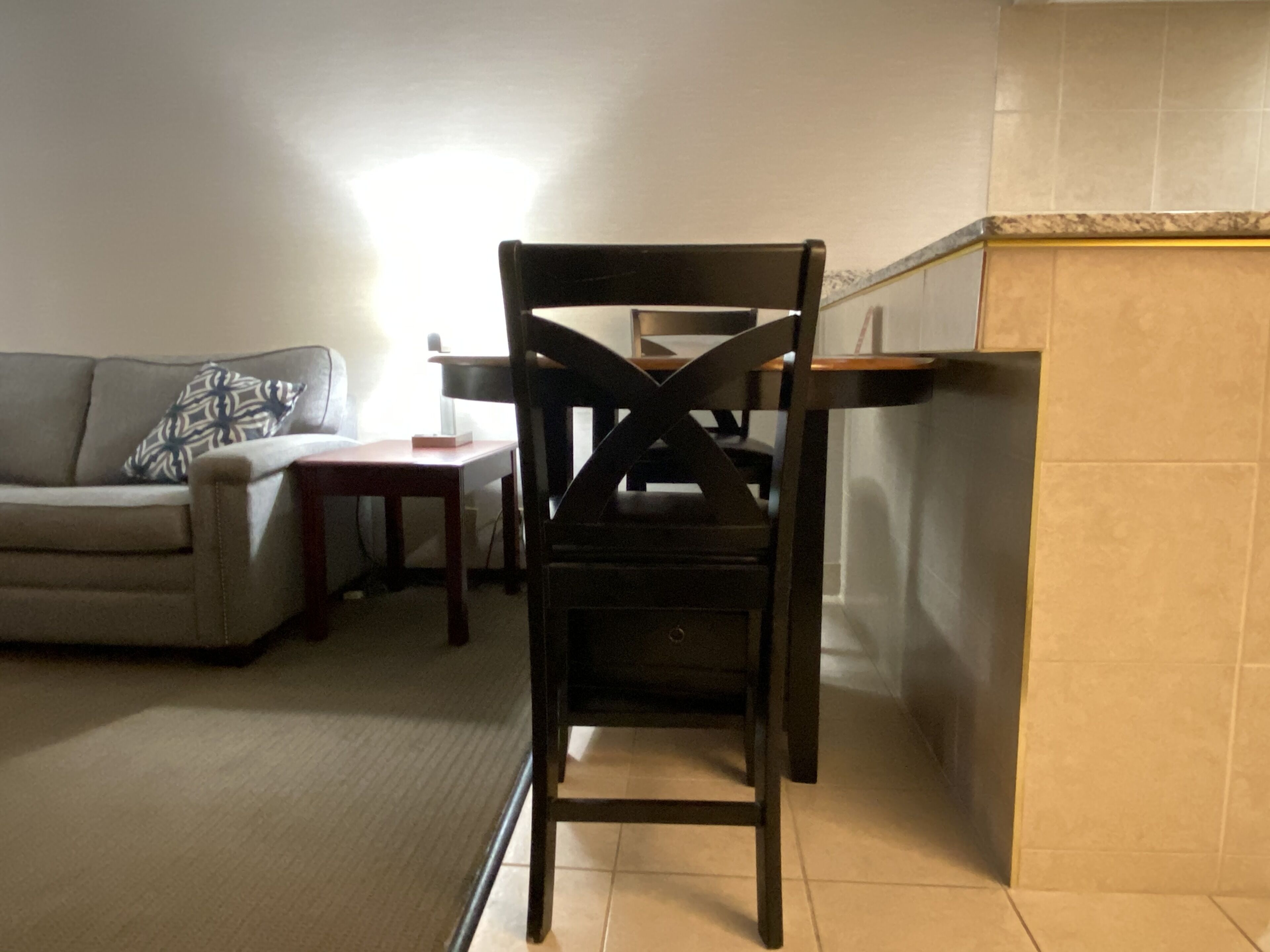 Una sala de estar con un sofá, una silla de madera, una mesita y una pared de azulejos.