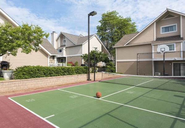 An outdoor basketball court with a net, surrounded by residential buildings.
