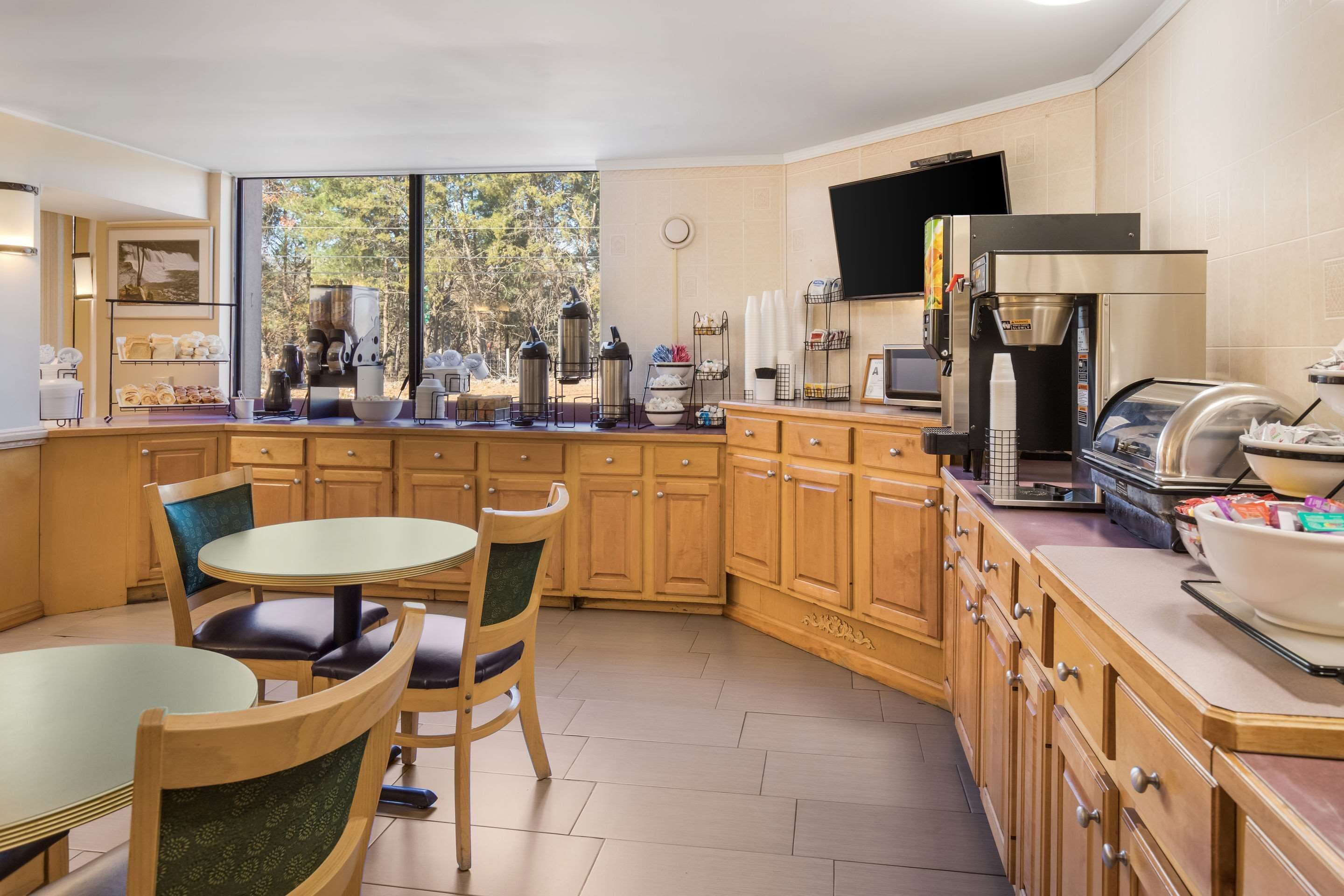 A modern kitchen with wooden cabinets, a round dining table, and a coffee machine.