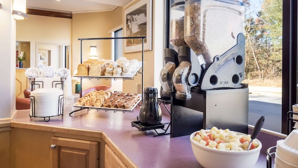 A breakfast buffet with pastries, a coffee machine, and a bowl of fruit. - Econo Lodge Hendersonville (Hendersonville)