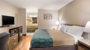 A hotel room with a bed, a desk, a television, a microwave, and a bathroom visible in the background. - Econo Lodge Hendersonville (Hendersonville)