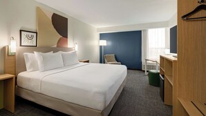 A hotel room with a large bed, a desk, a chair, and a wardrobe. - Spark by Hilton Nashville at Opryland (Nashville)