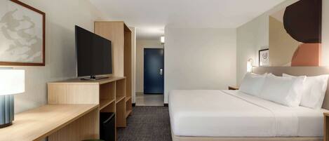 Una habitación de hotel con una cama, un escritorio, un televisor y un taburete verde.
