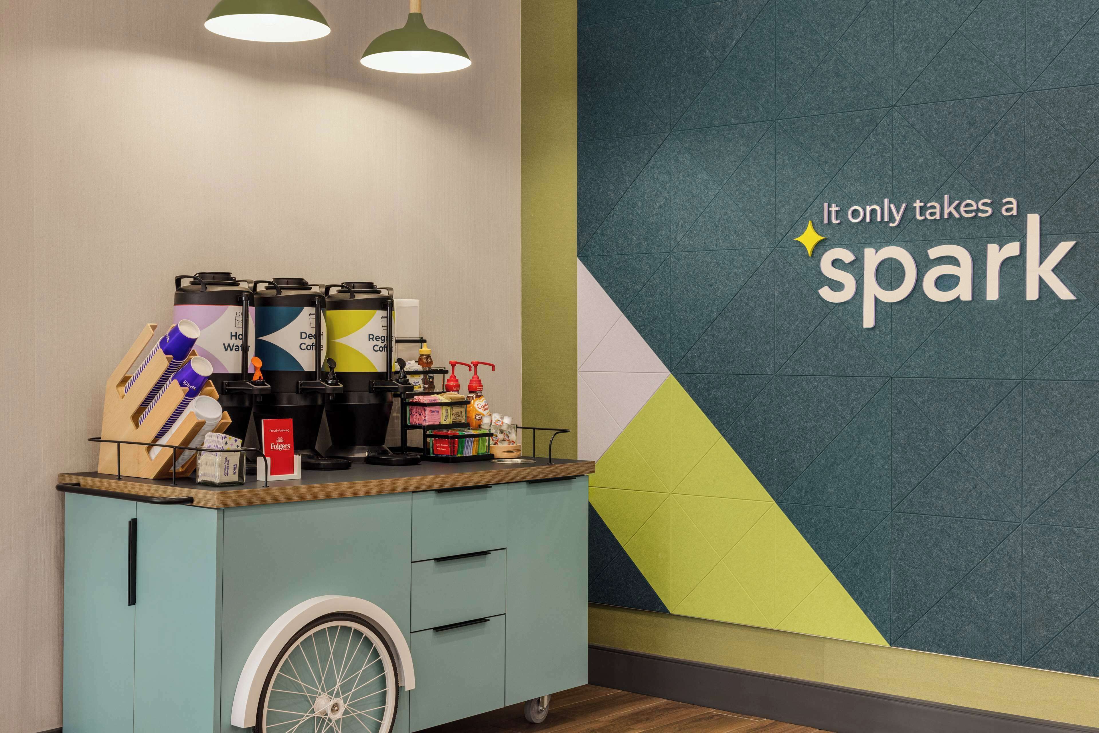 Una estación de café con un letrero en la pared que dice “Solo se necesita una chispa”.