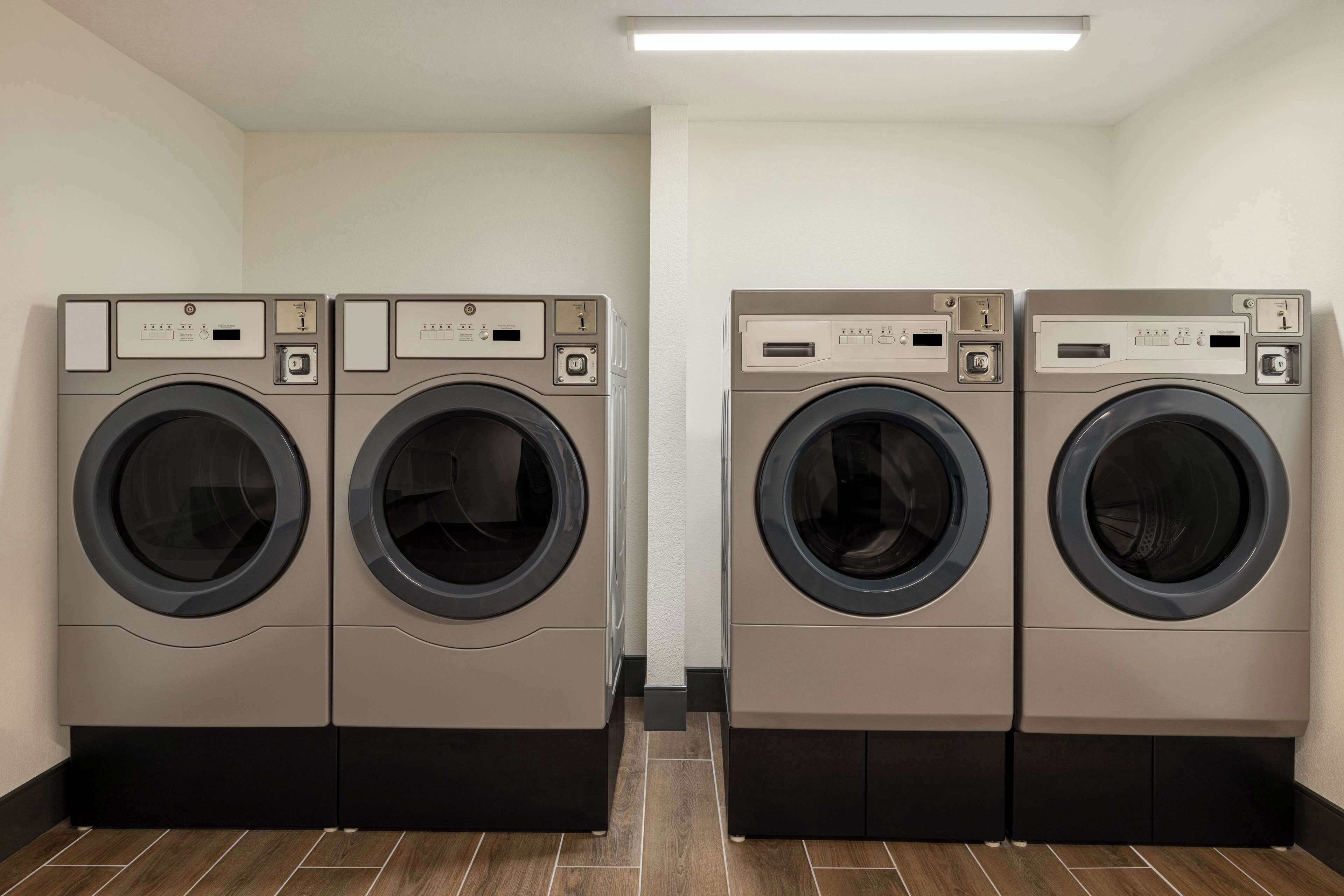 A laundry room with four front-loading washing machines and a tiled floor.