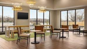A spacious indoor area with multiple seating arrangements, large windows, and modern lighting fixtures. - Spark by Hilton Nashville at Opryland (Nashville)