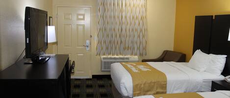 Une chambre d’hôtel avec deux lits, un bureau, une télévision et un appareil de climatisation.