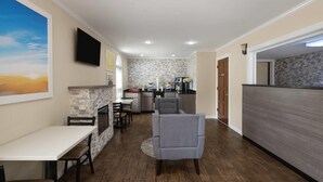 A modern kitchen with a stone backsplash, a dining area with a table and chairs, and a gray armchair. - Days Inn by Wyndham Canton (Canton)