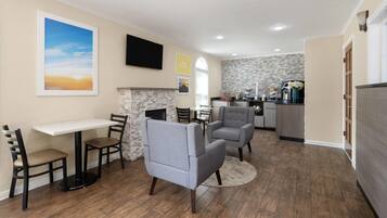 A dining area with a table and chairs, a fireplace, and a kitchen in the background.