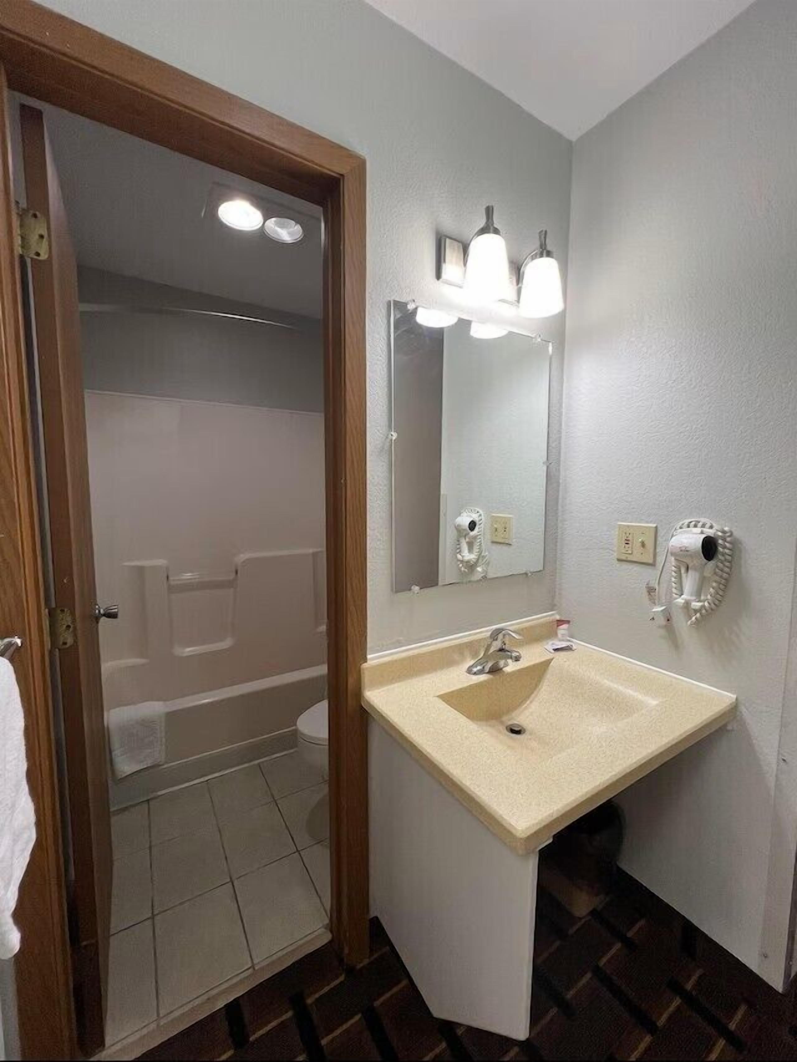 Un baño con lavamanos, espejo y ducha.