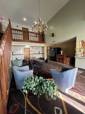 A hotel lobby with a chandelier, seating area, and a staircase.