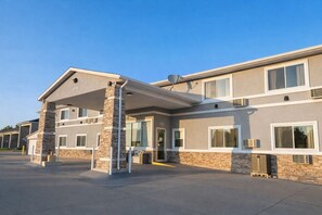 Ein mehrstöckiges Hotel mit überdachter Einfahrt, steinernen Säulen und großen Fenstern.
