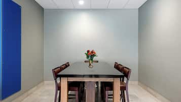 A conference room with a rectangular table, four chairs, and a vase with flowers.