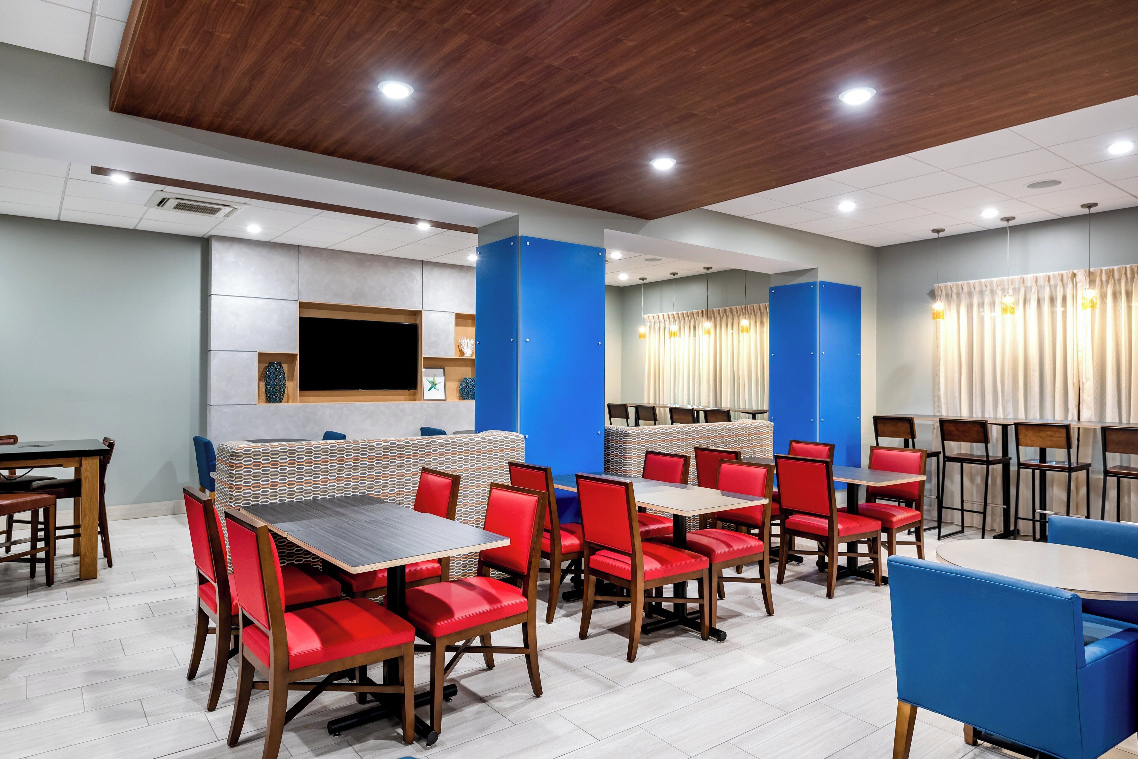 A restaurant with booths and tables, wooden flooring, and a modern ceiling design.