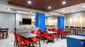 A restaurant with booths and tables, wooden flooring, and a modern ceiling design.