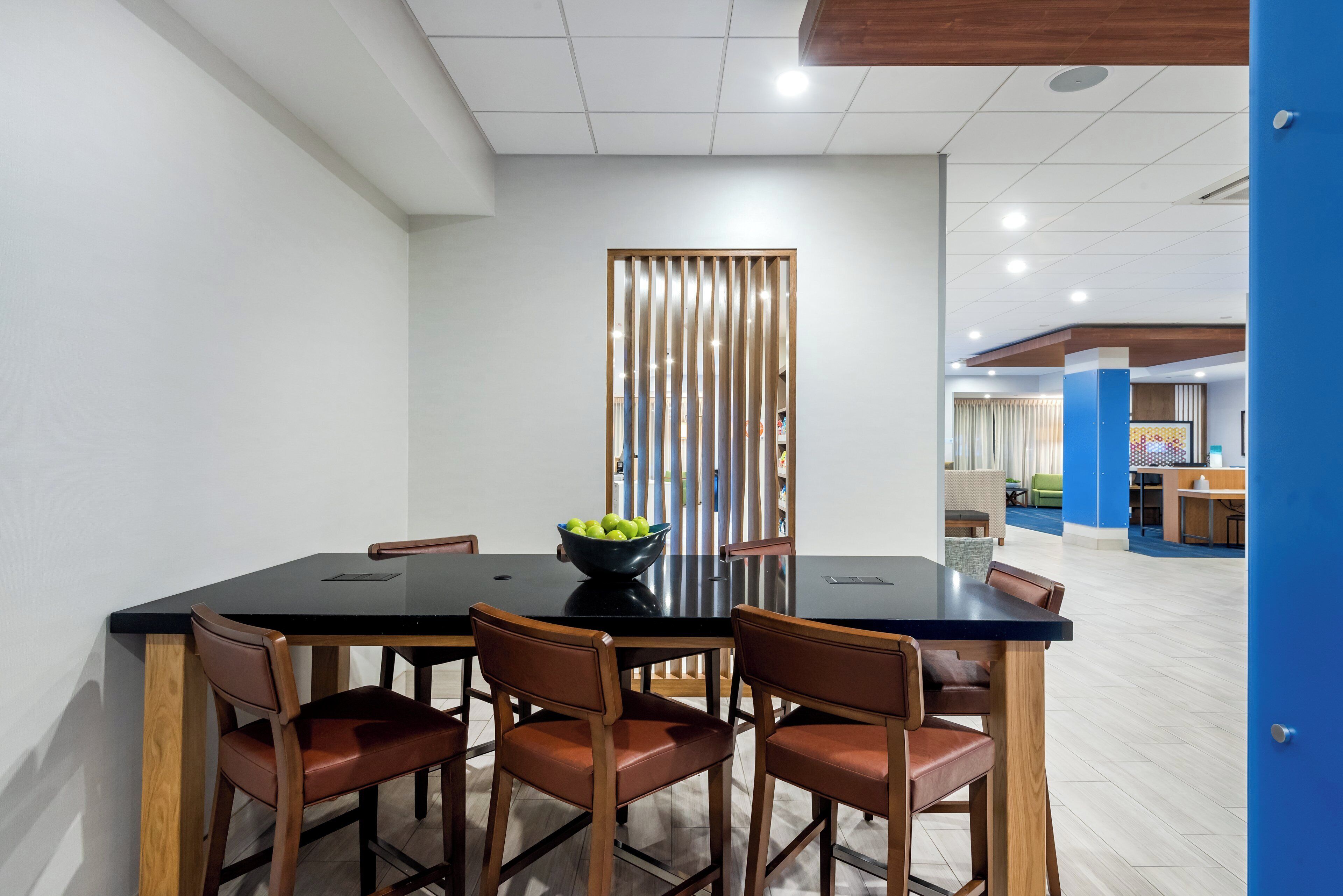 A conference room with a black table, six brown chairs, and a wooden partition.