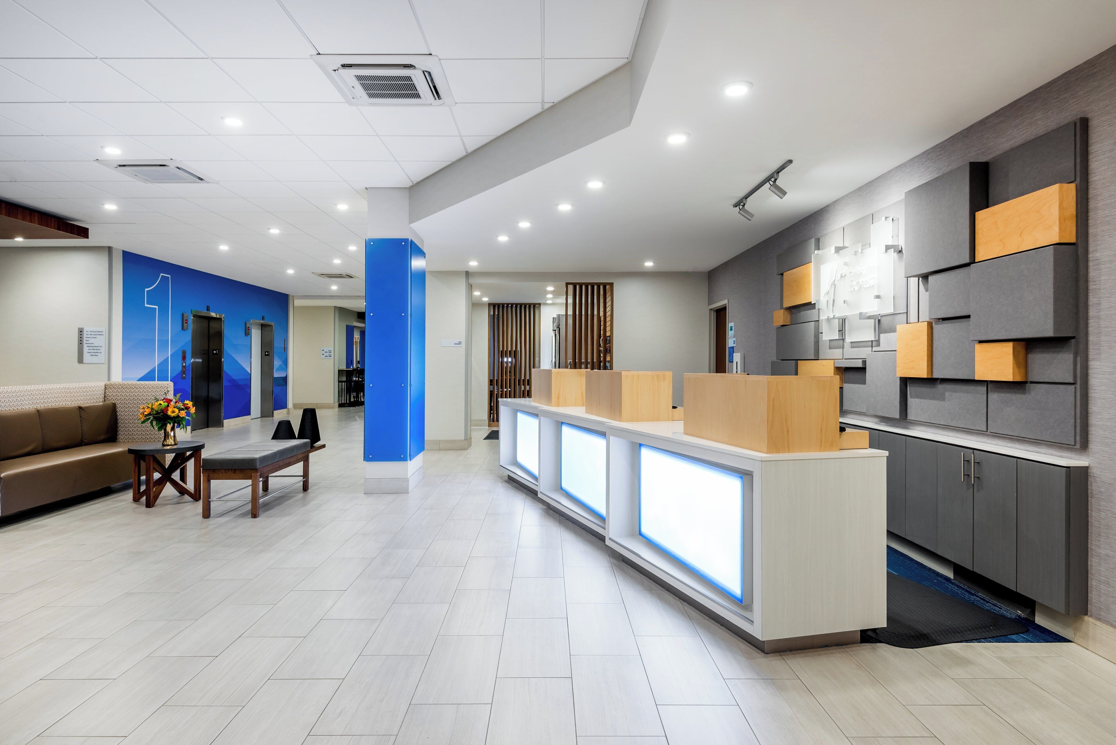 A modern reception area with a reception desk, seating area, and a counter with a digital display.