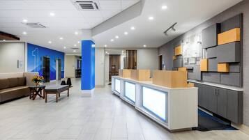 A modern reception area with a reception desk, seating area, and a counter with a digital display.