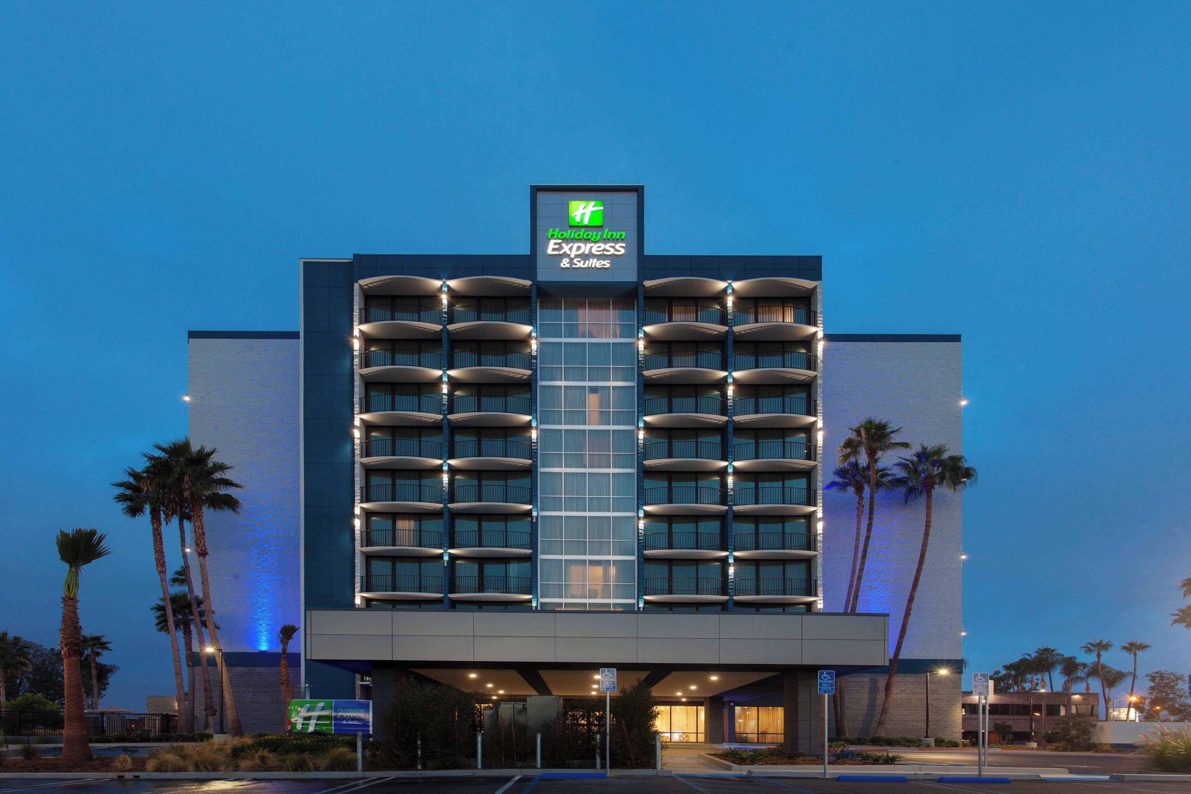 Un hotel Holiday Inn Express & Suites con un diseño arquitectónico moderno, que cuenta con varios balcones y una entrada destacada.