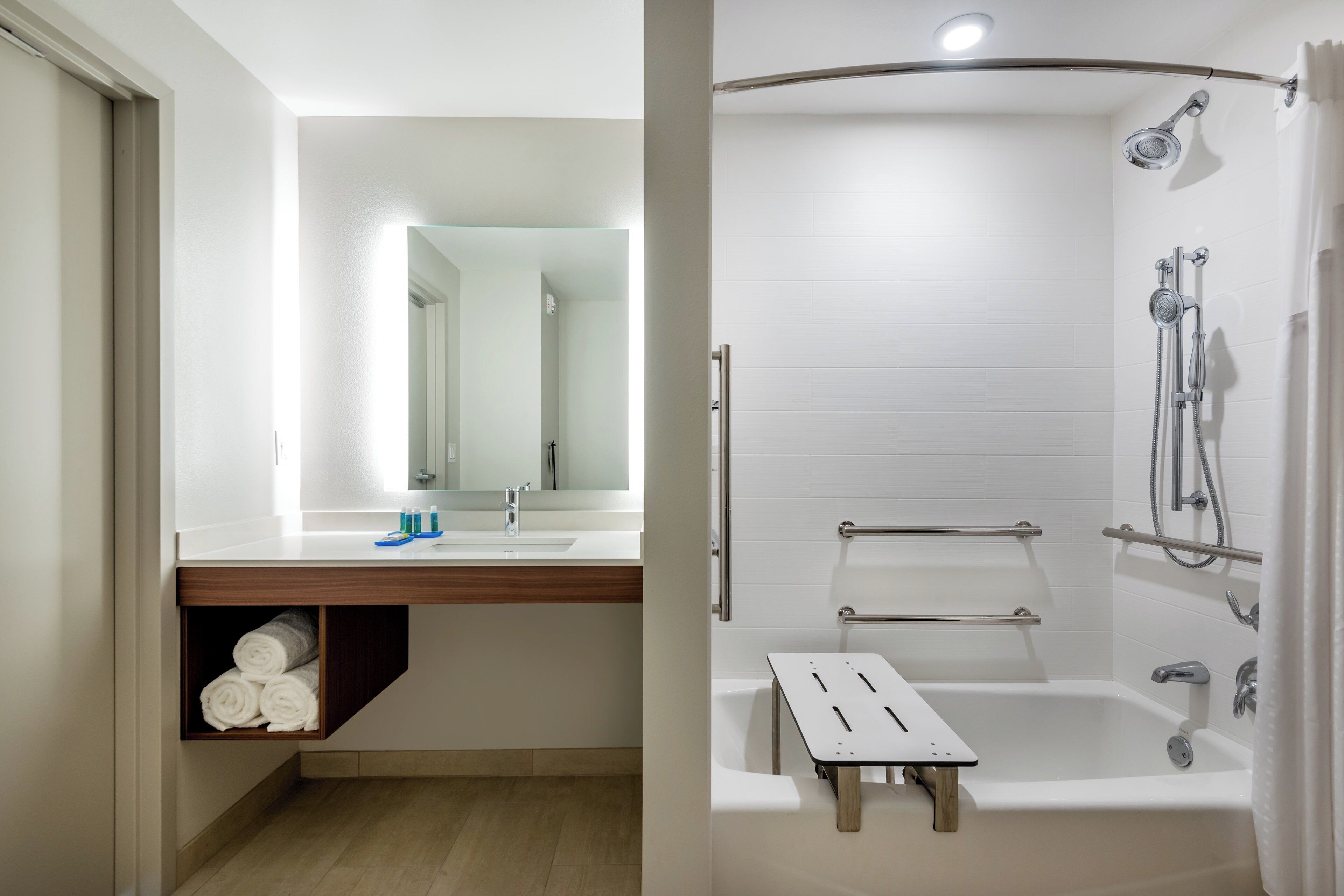 A bathroom with a sink, mirror, towel rack, and shower with a handheld showerhead.