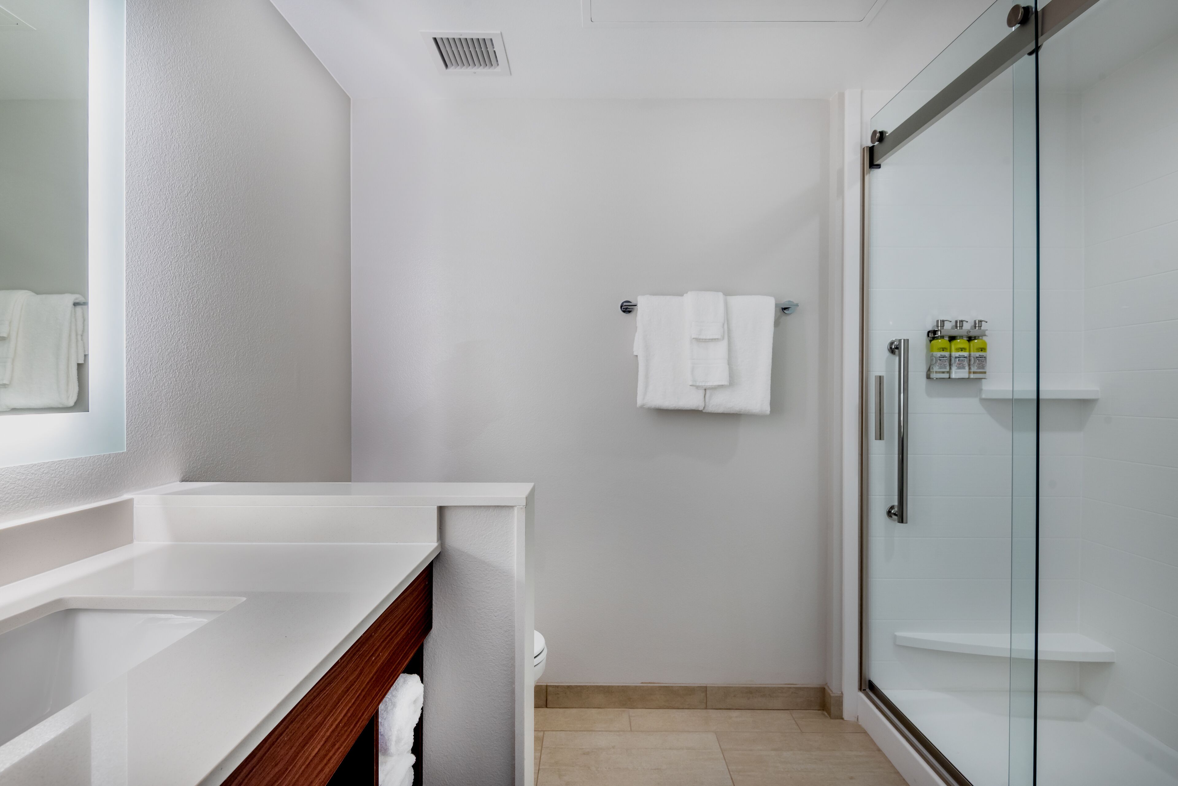 Une salle de bain moderne avec un meuble-lavabo blanc, une cabine de douche en verre et un porte-serviettes mural.