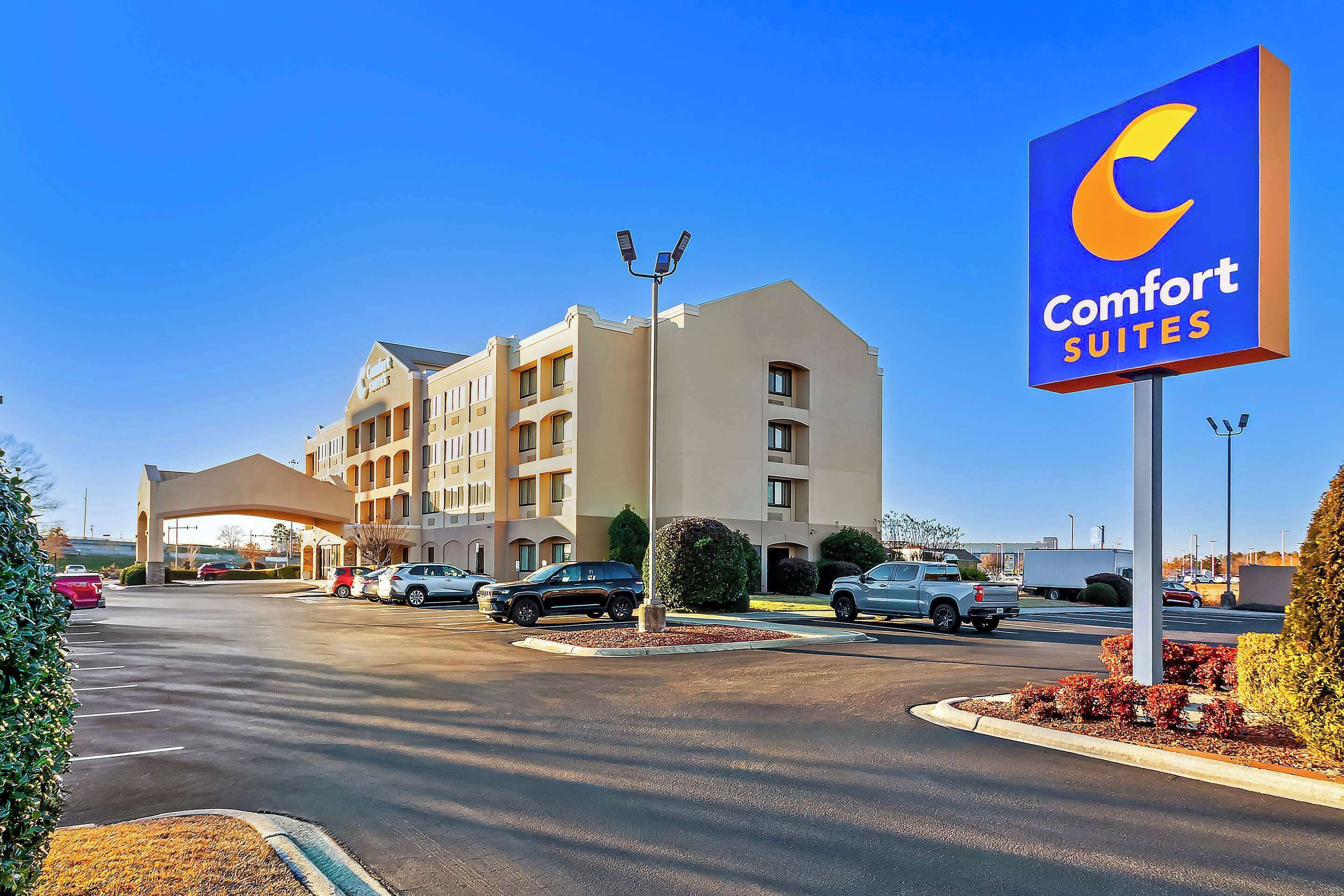 A Comfort Suites hotel with a large sign, a parking lot, and a building with multiple floors.