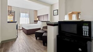 A hotel room with a bed, a seating area, a microwave, and a view of the hallway. - Comfort Suites Lumberton North (Lumberton)