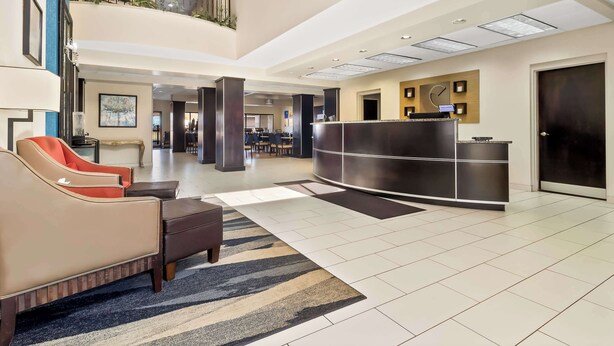 A hotel lobby with a reception desk, seating area, and a staircase. - Comfort Suites Lumberton North (Lumberton)