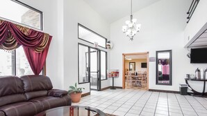 A spacious living area with a leather sofa, a glass coffee table, and a chandelier.