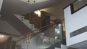 Un intérieur moderne agrémenté d’un escalier en verre, d’un lustre en cristal décoratif et de rampes d’escalier apparentes.