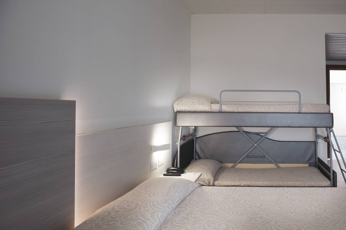 A bunk bed with a headboard and a lower bed, both with patterned bedding.