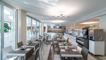 Un restaurante moderno con una barra larga, varias mesas y sillas.