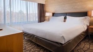 Quarto de hotel com cama grande, mesa de cabeceira, abajur e telefone.