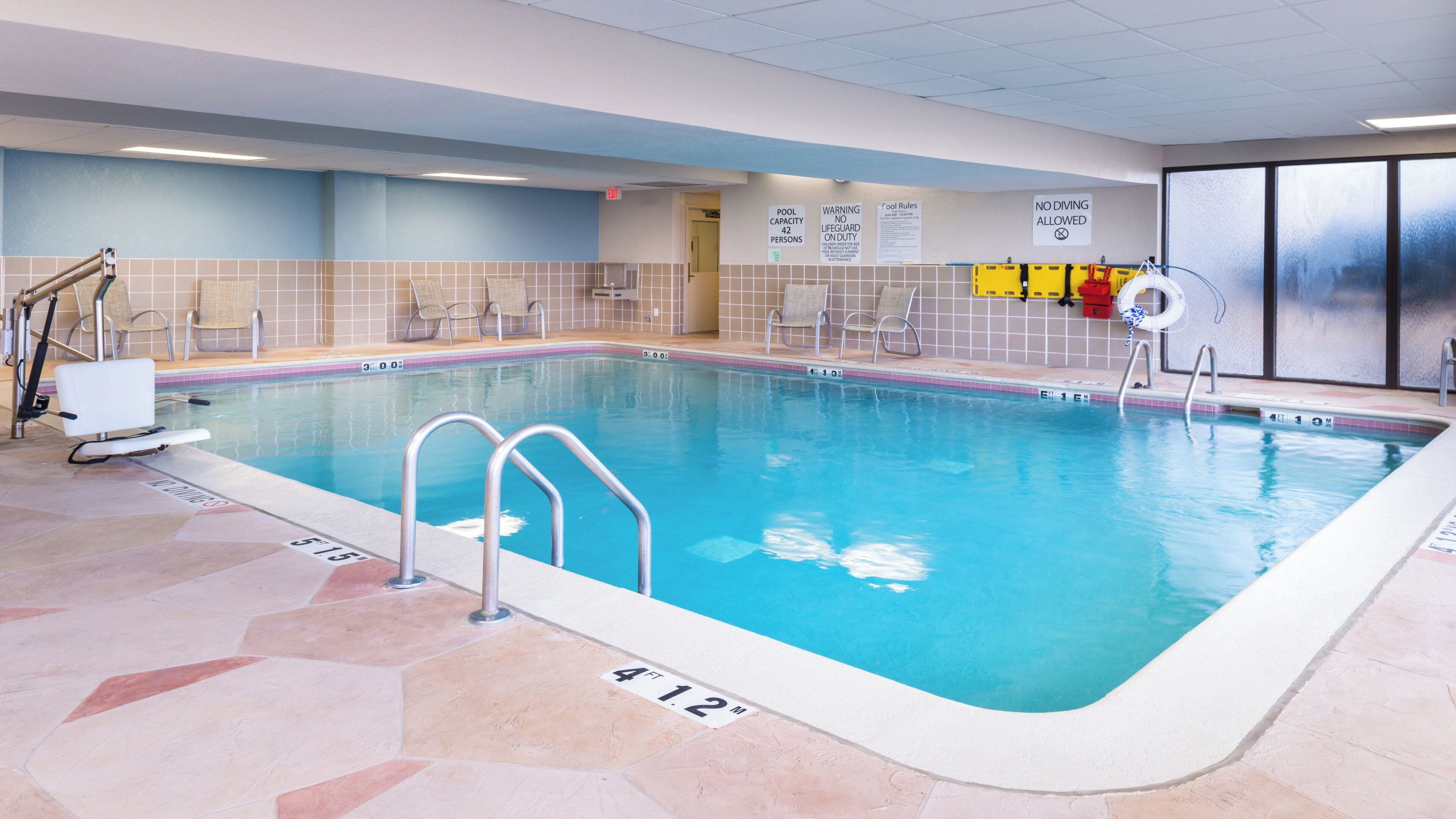 An indoor swimming pool with clear water, marked depth, and safety signs.