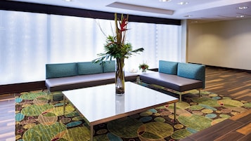 Una sala de conferencias moderna con una mesa de vidrio, asientos acolchados y un centro de mesa con planta decorativa.