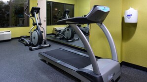 A gym with a treadmill, stationary bike, and a Purell sanitizer dispenser. - Holiday Inn Hotel & Suites Warren by IHG (Warren)