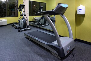 Un gimnasio con cinta de correr, bicicleta estática y dispensador de Purell.