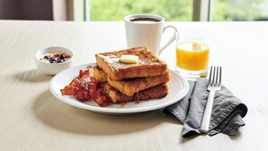 A breakfast plate with French toast, bacon, and a small bowl of blueberries. - Holiday Inn Hotel & Suites Warren by IHG (Warren)
