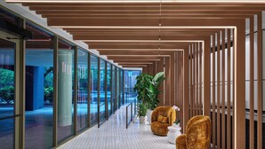 A modern interior with a glass corridor, wooden slats, and seating areas. - One Washington Circle DC, Tapestry Collection by Hilton (Washington)
