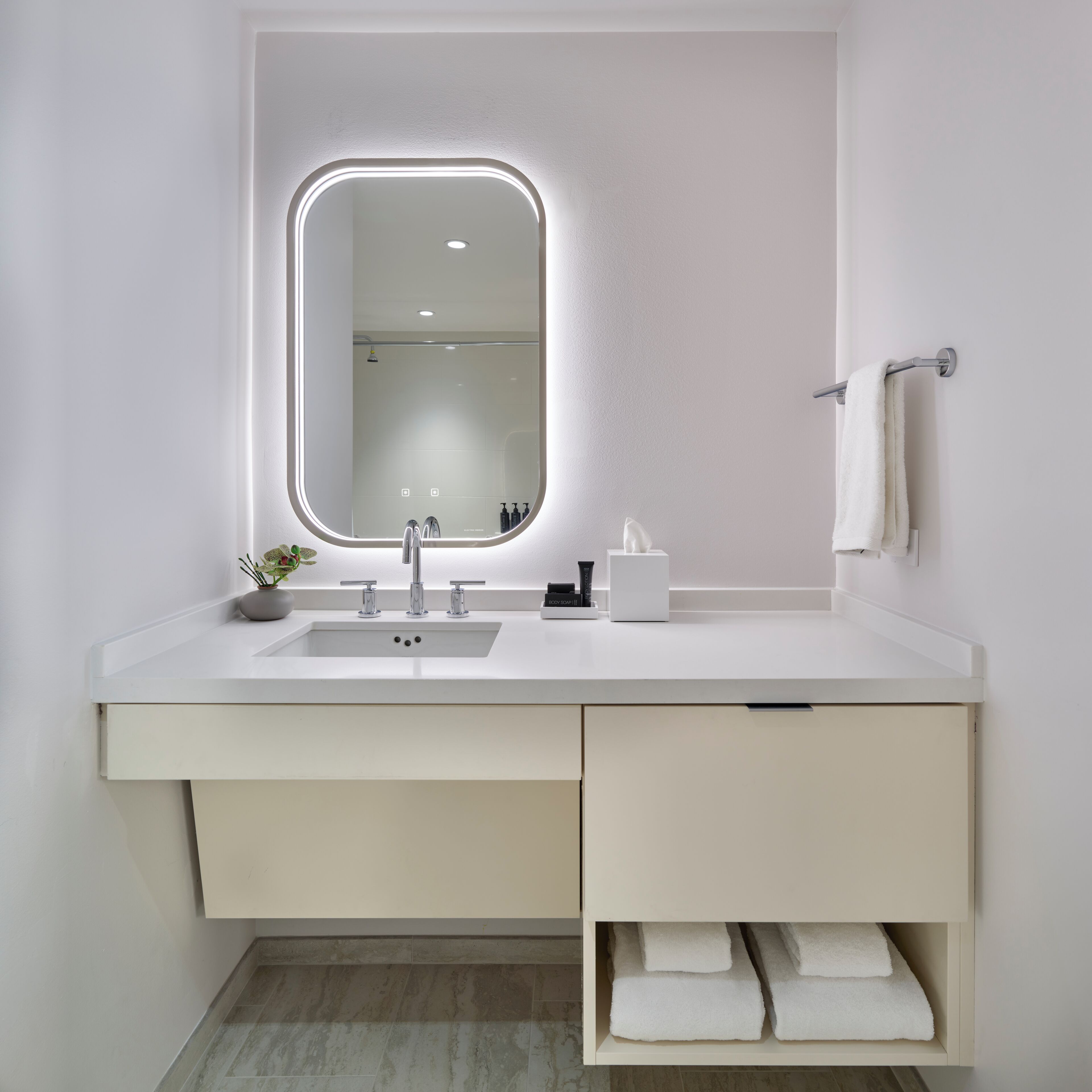 Un baño moderno con un espejo grande, un lavabo y un perchero para toallas.