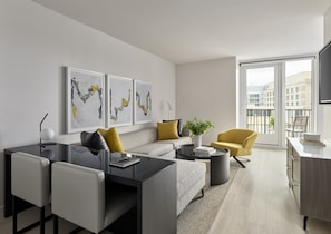 A modern living room with a sofa, coffee table, and chairs, a dining area with a table and chairs, and artwork on the wall. - One Washington Circle DC, Tapestry Collection by Hilton (Washington)