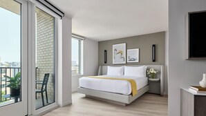 A modern bedroom with a large bed, a bedside table with a vase, and artwork on the wall. - One Washington Circle DC, Tapestry Collection by Hilton (Washington)