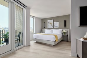 A modern bedroom with a large bed, a bedside table with a vase, and artwork on the wall. - One Washington Circle DC, Tapestry Collection by Hilton (Washington)