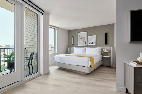 A modern bedroom with a large bed, a bedside table with a vase, and artwork on the wall. - One Washington Circle DC, Tapestry Collection by Hilton (Washington)